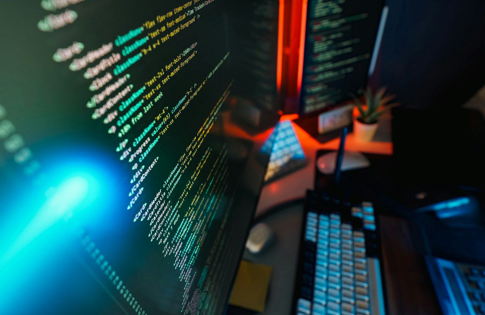 Close-up of a computer screen filled with colorful programming code under blue and red ambient light