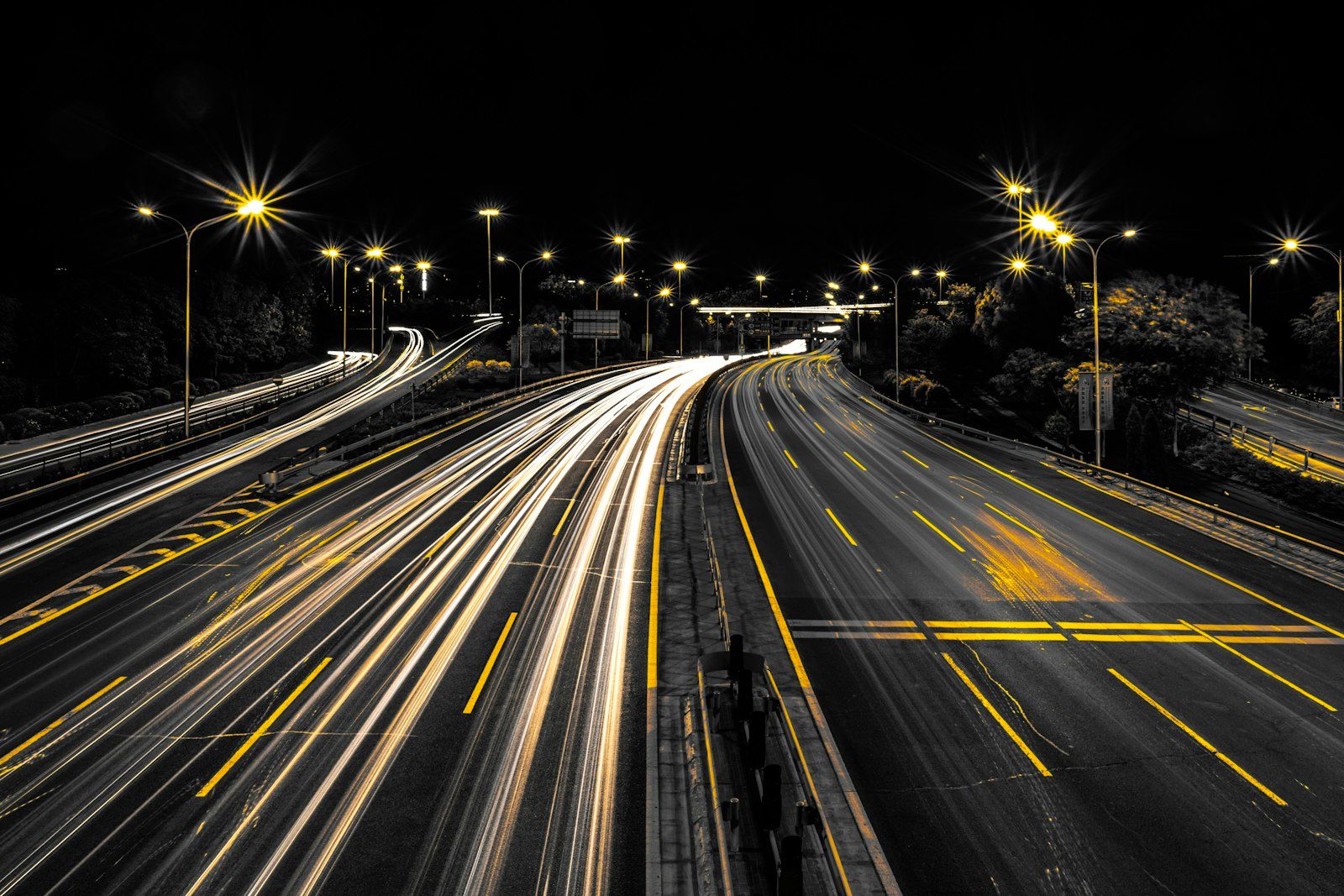 Highway at night with golden light trails — traffic taking the exit